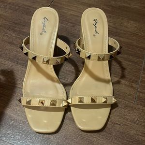 Tan block heel slip on heels. Gold hardware on both straps.